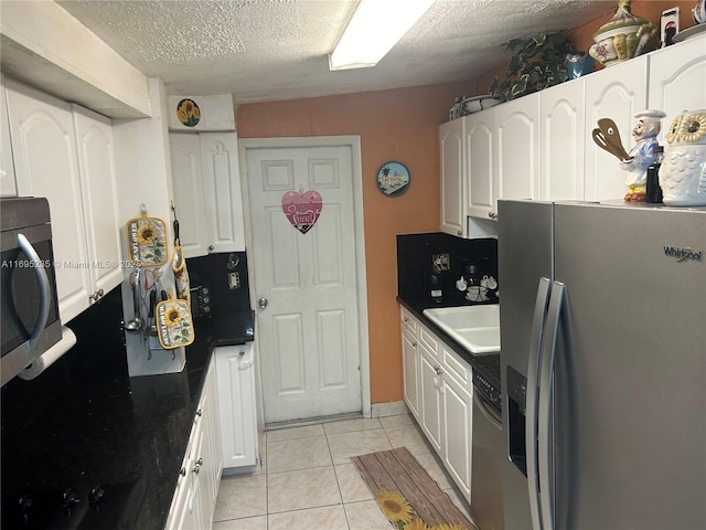 kitchen with light tile patterned flooring, sink, white cabinetry, and stainless steel appliances