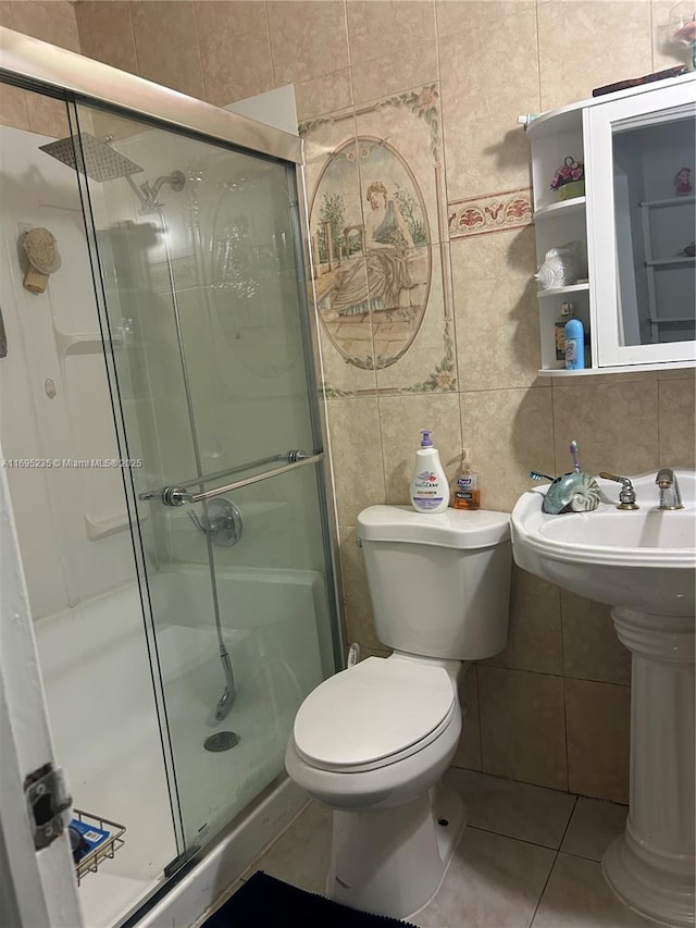 bathroom with tile patterned floors, toilet, decorative backsplash, a shower with shower door, and tile walls