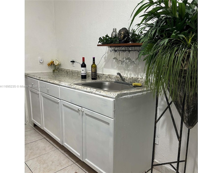 kitchen featuring white cabinetry, sink, and light tile patterned flooring