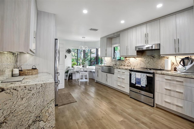 kitchen featuring an inviting chandelier, sink, stainless steel stove, decorative light fixtures, and light hardwood / wood-style floors