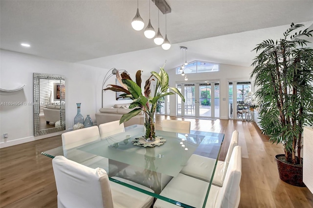 dining area with french doors, light hardwood / wood-style floors, and lofted ceiling