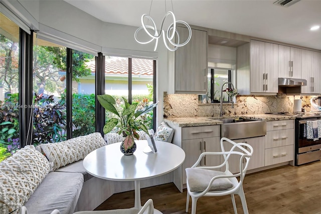 kitchen with stainless steel electric stove, plenty of natural light, decorative backsplash, and hardwood / wood-style floors