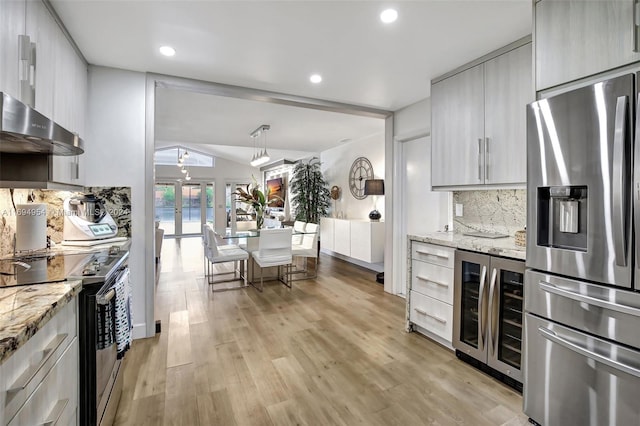 kitchen featuring wine cooler, light hardwood / wood-style flooring, vaulted ceiling, decorative light fixtures, and stainless steel appliances