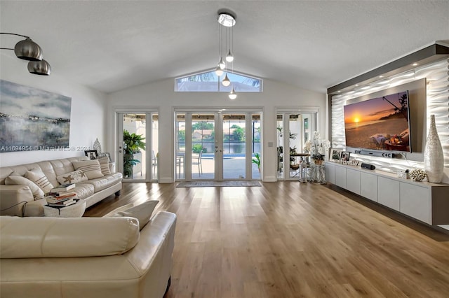 living room featuring a textured ceiling, french doors, vaulted ceiling, and light hardwood / wood-style flooring