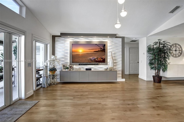 living room featuring hardwood / wood-style floors, vaulted ceiling, and a healthy amount of sunlight