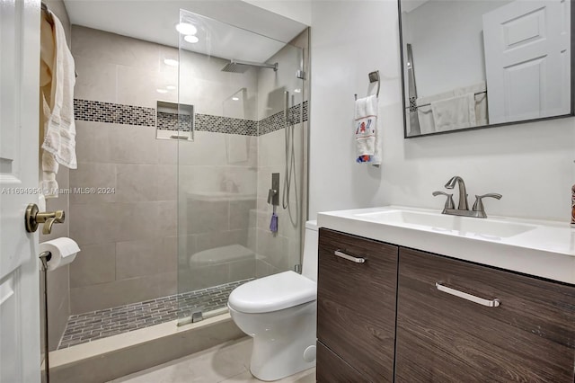 bathroom with tile patterned floors, a shower with door, vanity, and toilet