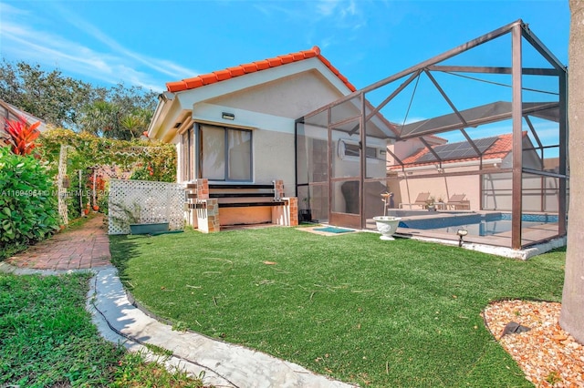 rear view of property featuring glass enclosure, a swimming pool with hot tub, a patio area, and a yard