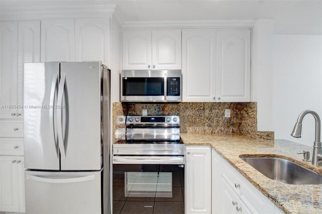 kitchen with light stone countertops, sink, white cabinets, and appliances with stainless steel finishes