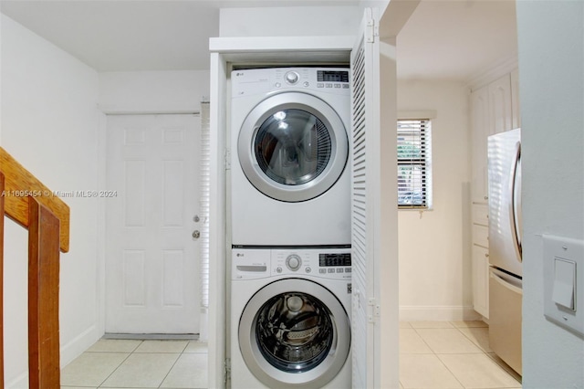 laundry room featuring stacked washing maching and dryer and light tile patterned floors