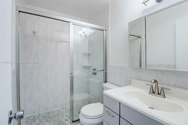 bathroom featuring walk in shower, vanity, tile walls, and toilet