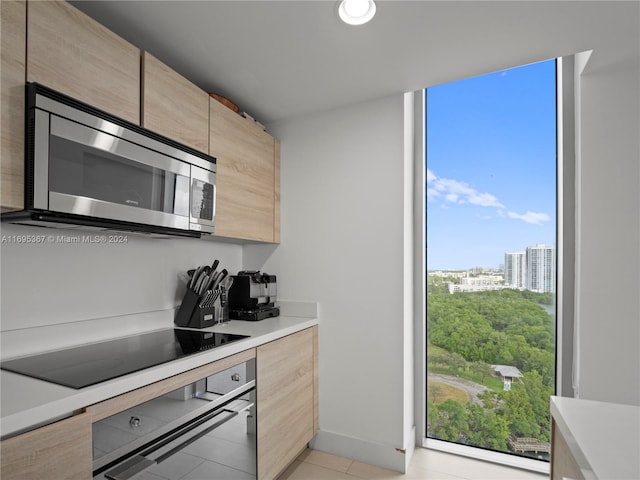 kitchen with appliances with stainless steel finishes, light tile patterned floors, and light brown cabinetry