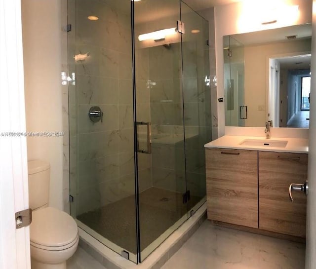 bathroom with vanity, toilet, and a shower with shower door