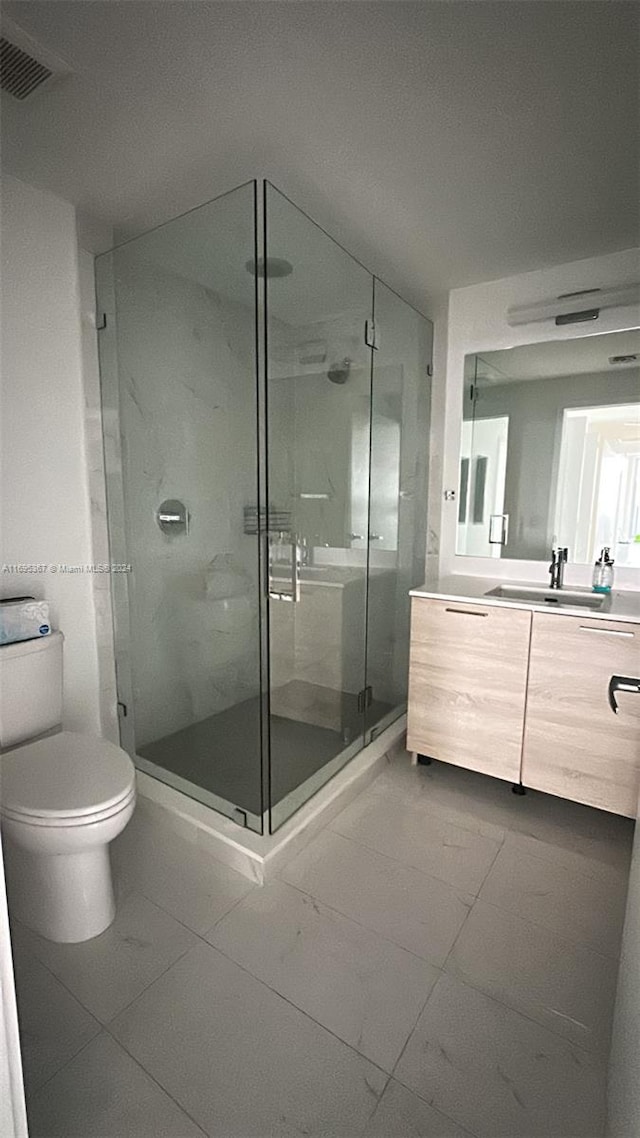 bathroom with tile patterned floors, vanity, toilet, and a shower with door