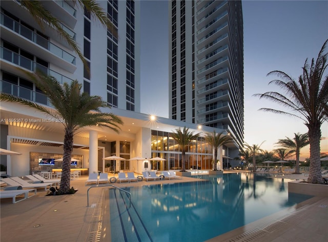 pool at dusk featuring a patio