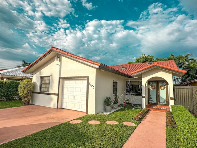 mediterranean / spanish house featuring a front lawn, a garage, and french doors