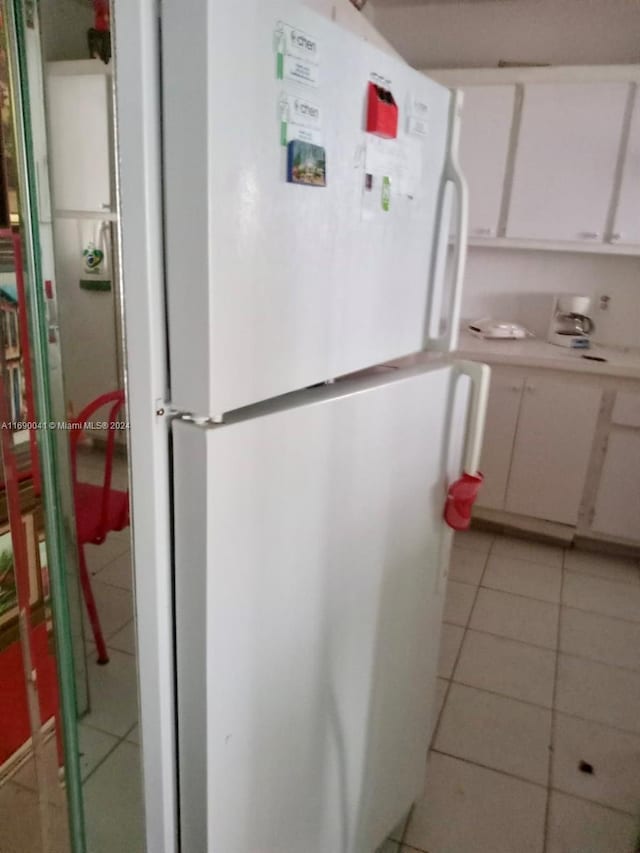 kitchen featuring white cabinets, white refrigerator, and light tile patterned flooring