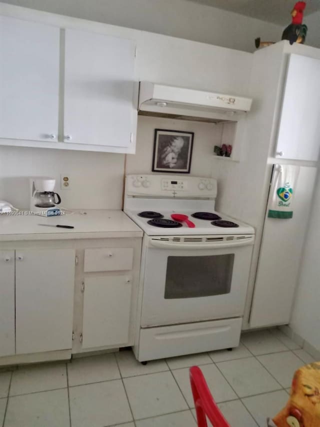 kitchen with light tile patterned floors, ventilation hood, white cabinetry, and electric stove