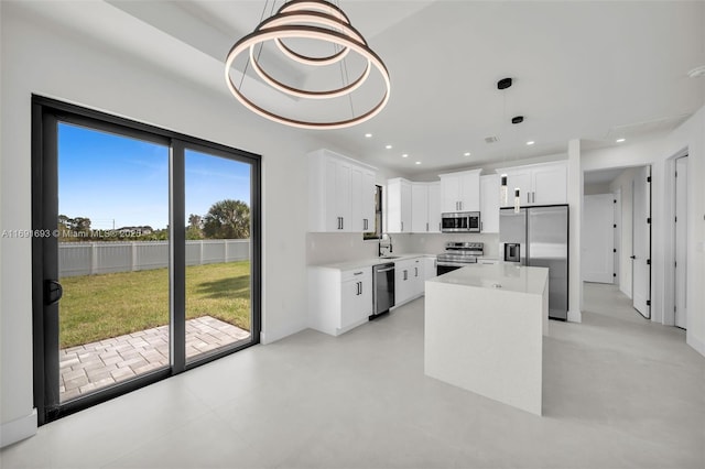 kitchen with white cabinetry, appliances with stainless steel finishes, decorative light fixtures, and a center island