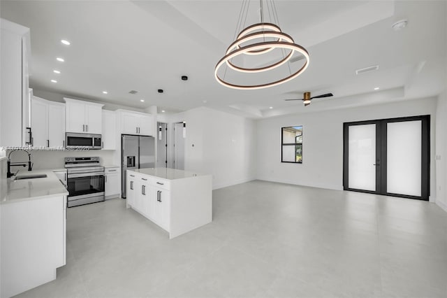 kitchen featuring sink, a raised ceiling, pendant lighting, stainless steel appliances, and white cabinets