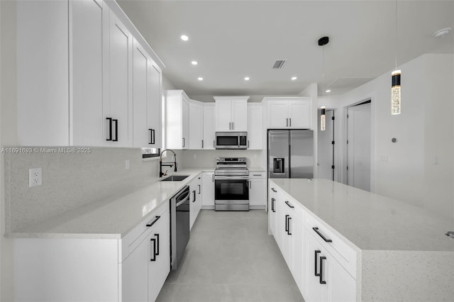 kitchen with decorative light fixtures, white cabinetry, sink, a center island, and stainless steel appliances