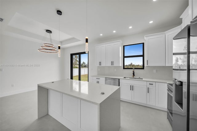 kitchen with sink, hanging light fixtures, stainless steel appliances, white cabinets, and a raised ceiling