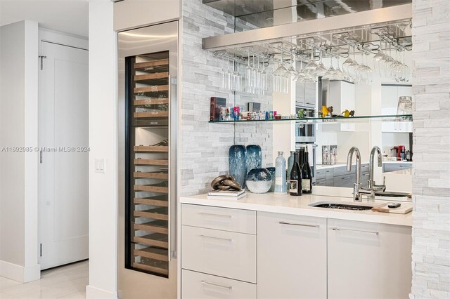 bar featuring wine cooler, sink, white cabinets, and light tile patterned flooring