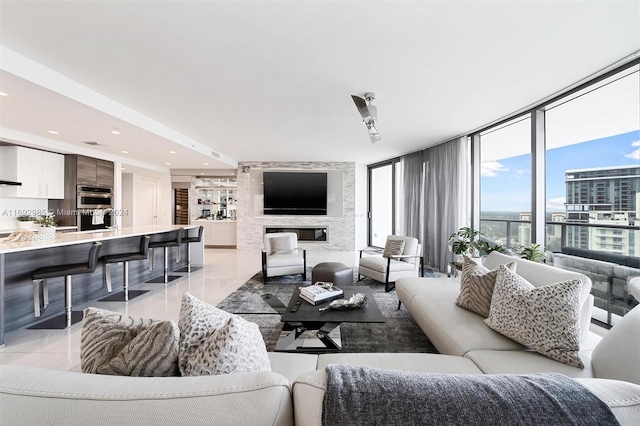 living room featuring a large fireplace, a wall of windows, and light tile patterned floors