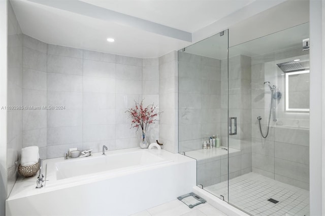 bathroom with tile patterned flooring, tile walls, and independent shower and bath