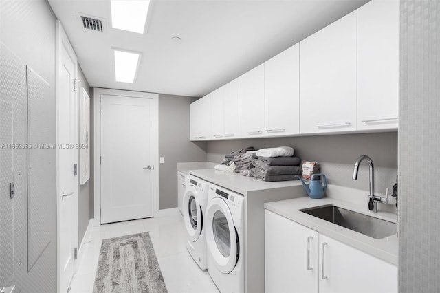 washroom with washing machine and clothes dryer, sink, light tile patterned floors, and cabinets