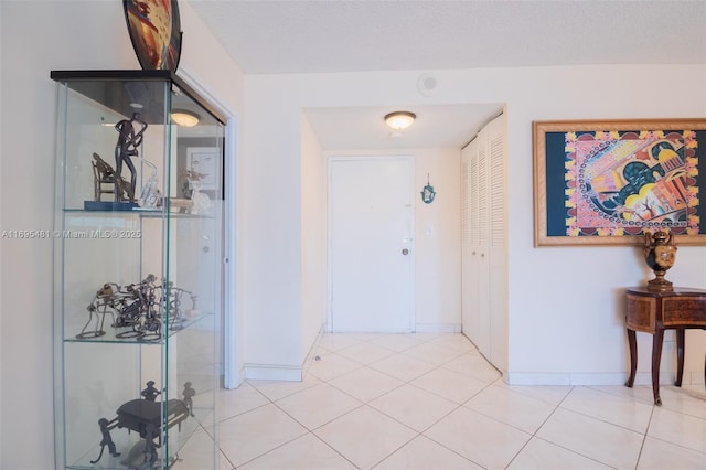 corridor with light tile patterned floors and a textured ceiling