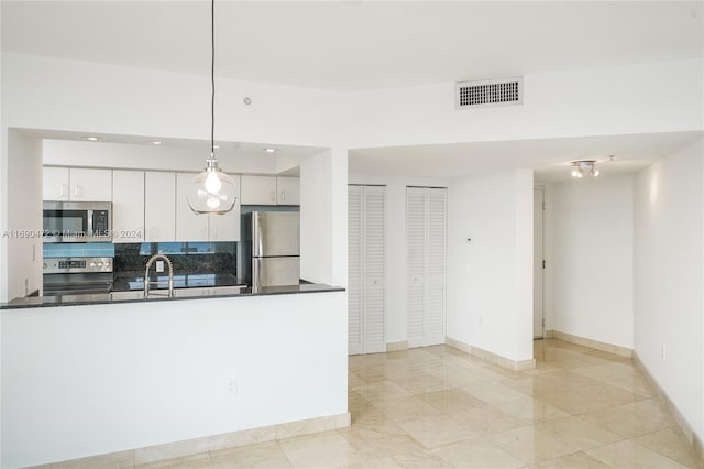 kitchen featuring white cabinets, sink, hanging light fixtures, decorative backsplash, and appliances with stainless steel finishes