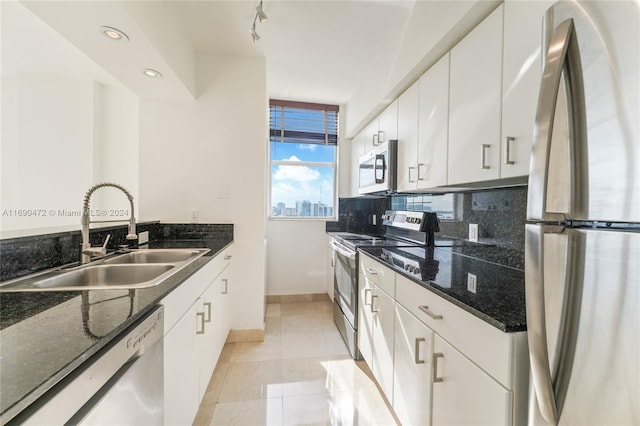 kitchen featuring white cabinetry, sink, stainless steel appliances, dark stone countertops, and decorative backsplash