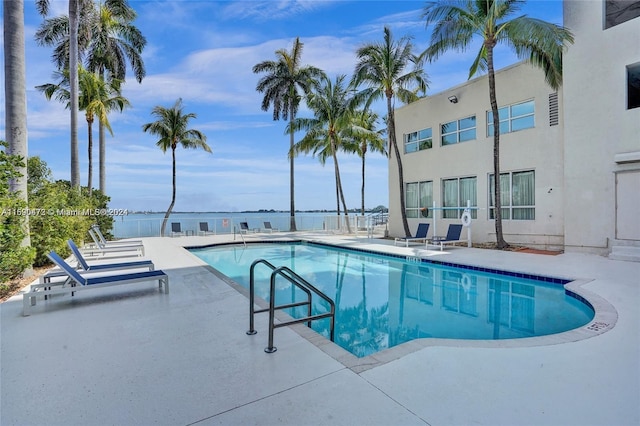 view of swimming pool with a patio area and a water view