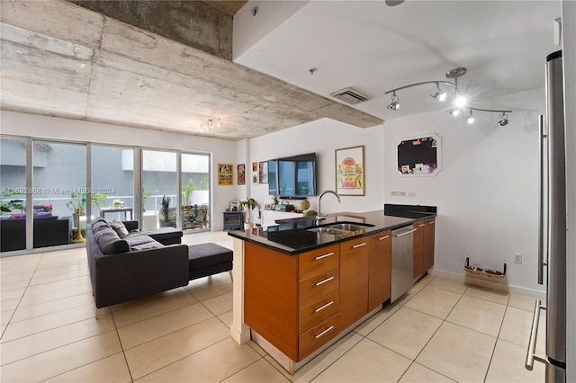 kitchen with kitchen peninsula, sink, light tile patterned flooring, and appliances with stainless steel finishes