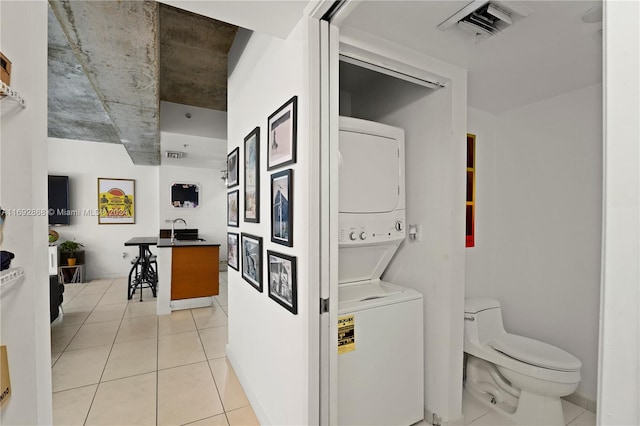 laundry room with stacked washing maching and dryer and light tile patterned floors