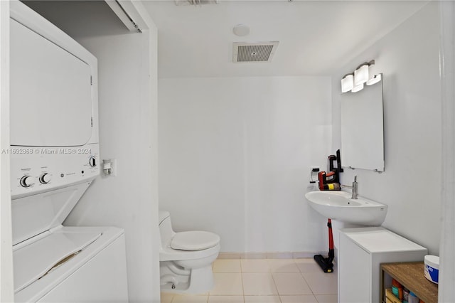 bathroom with tile patterned flooring, stacked washer and dryer, toilet, and sink