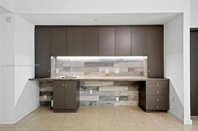 kitchen featuring dark brown cabinets, tasteful backsplash, light tile patterned floors, and sink