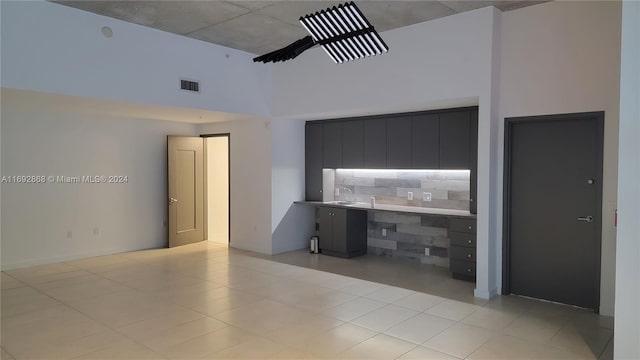 interior space featuring sink, light tile patterned floors, built in desk, and a high ceiling