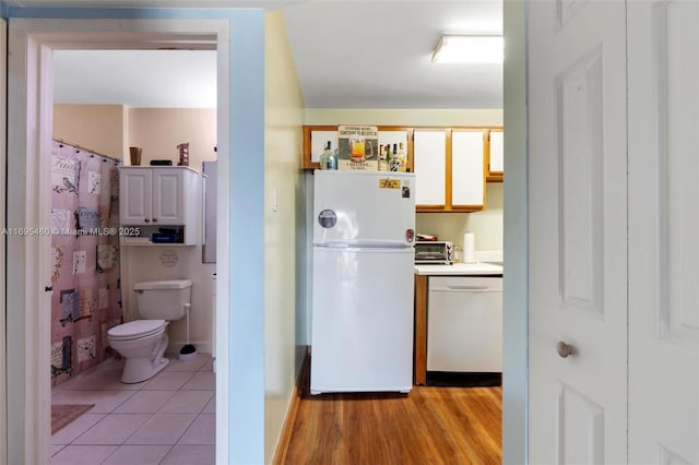 kitchen featuring white cabinets, light hardwood / wood-style flooring, white fridge, and dishwasher