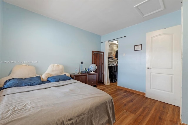 bedroom featuring a closet, a spacious closet, and dark hardwood / wood-style flooring