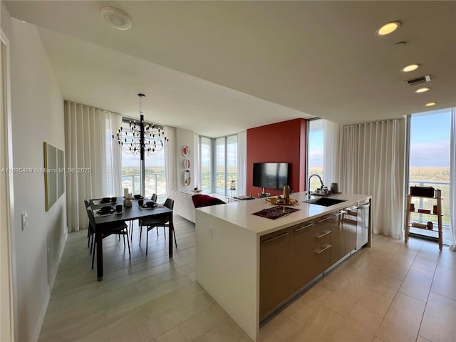 kitchen with an island with sink, a notable chandelier, hanging light fixtures, stainless steel dishwasher, and sink