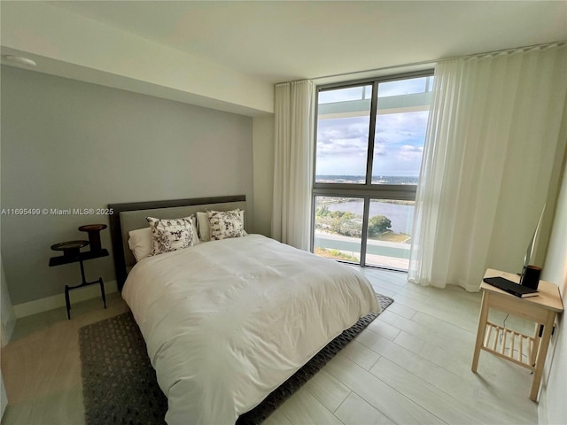 bedroom with a water view, expansive windows, and access to exterior