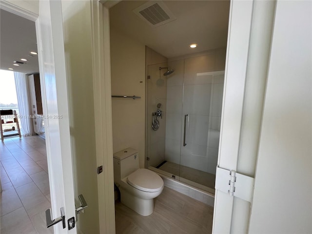 bathroom featuring toilet, tile patterned floors, and a shower with door