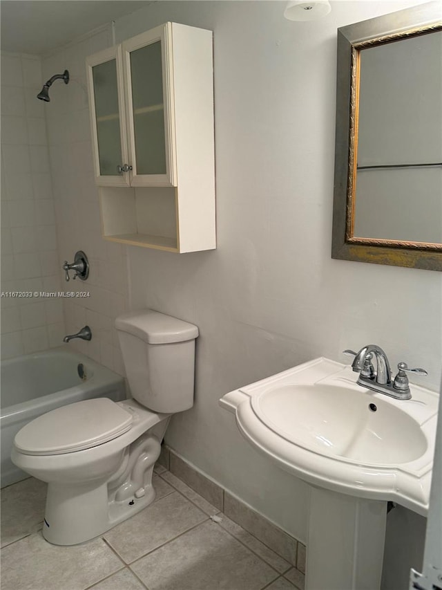 bathroom featuring tile patterned flooring, toilet, and tiled shower / bath