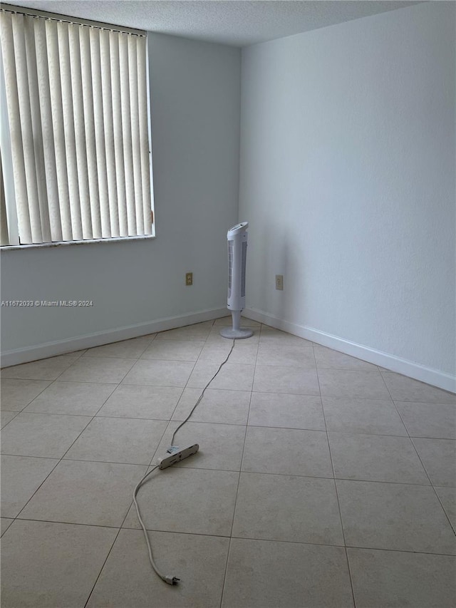 unfurnished room with a textured ceiling and light tile patterned flooring