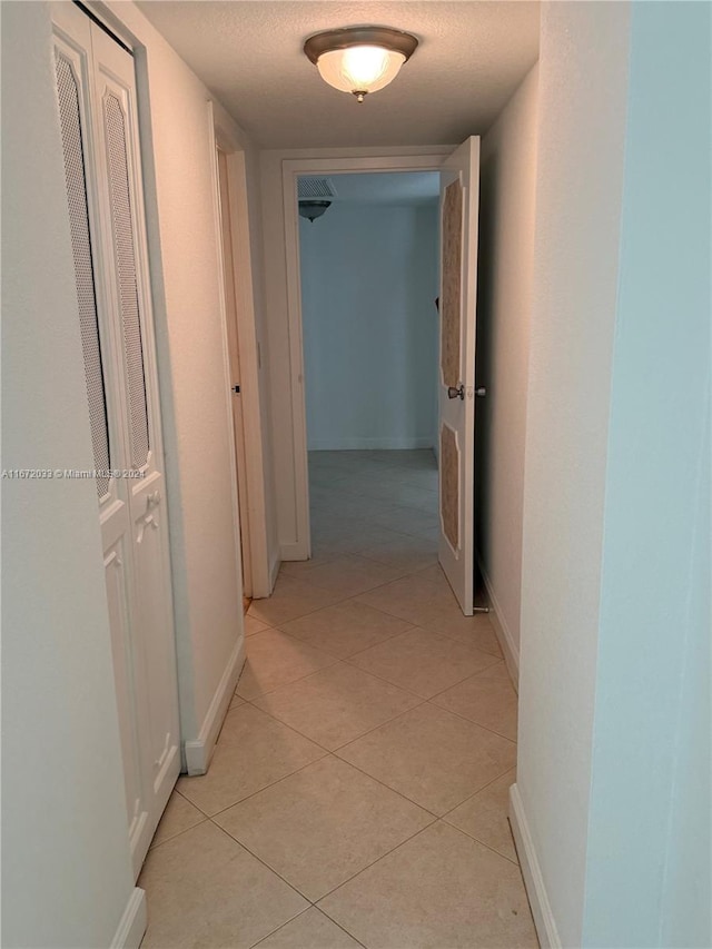 hall with light tile patterned floors and a textured ceiling