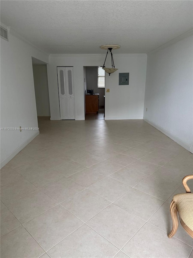 tiled empty room featuring electric panel, crown molding, and a textured ceiling