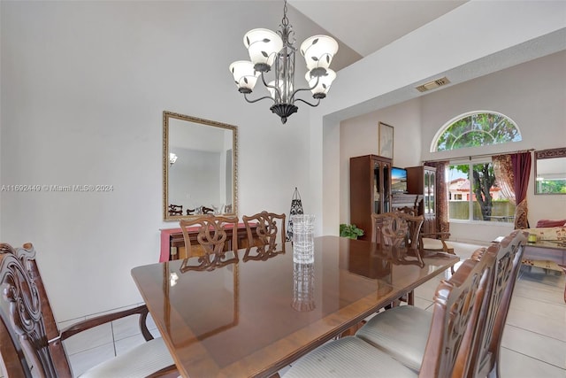 dining space with light tile patterned floors, a towering ceiling, and a chandelier