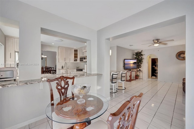 tiled dining space with ceiling fan with notable chandelier