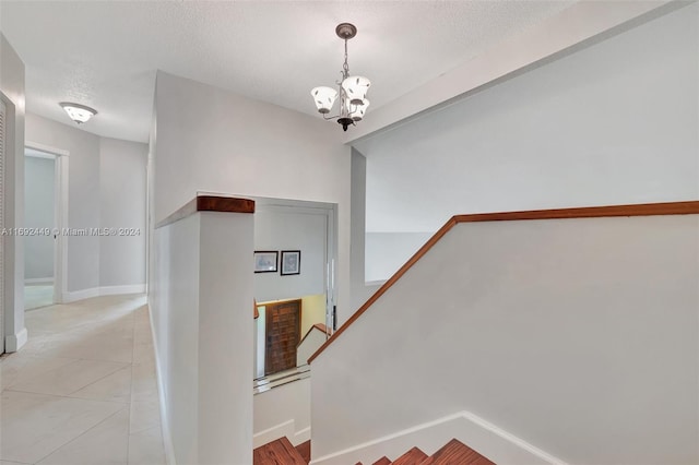 staircase featuring tile patterned flooring, a textured ceiling, and a chandelier